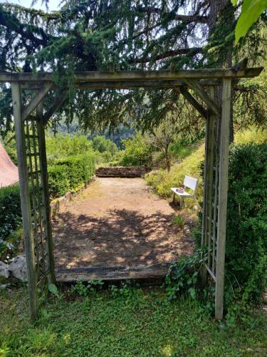 eine hölzerne Pergola mit einer Bank im Garten in der Unterkunft Val Paradis in Espagnac-Sainte-Eulalie