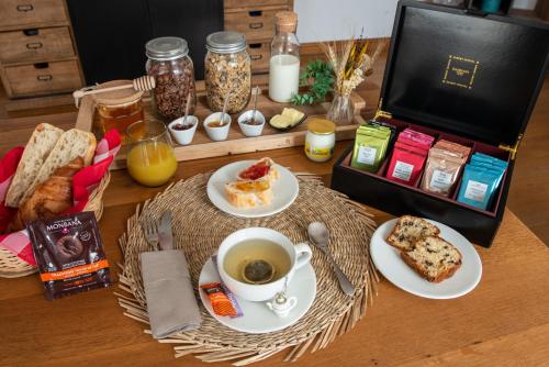 une table garnie d'assiettes de nourriture et d'une tasse de café dans l'établissement Couvent des Cordelières SPA en supplément, à Vezins