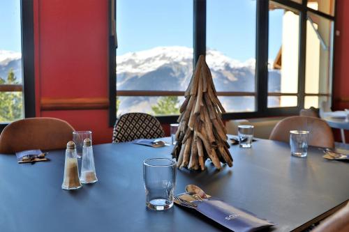 a table in a restaurant with mountains in the background at SOWELL Family La Lauzière in Aime La Plagne