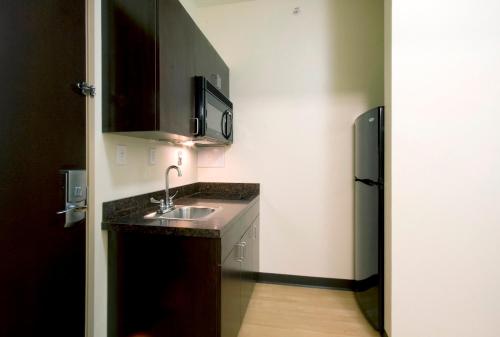 a small kitchen with a sink and a refrigerator at Red Roof Inn & Suites Beaumont in Beaumont