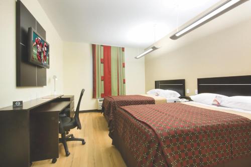 a hotel room with two beds and a desk and a television at Red Roof Inn & Suites Beaumont in Beaumont