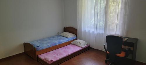 ein kleines Schlafzimmer mit 2 Einzelbetten und einem Stuhl in der Unterkunft Nice House next to a beautiful park in Tirana