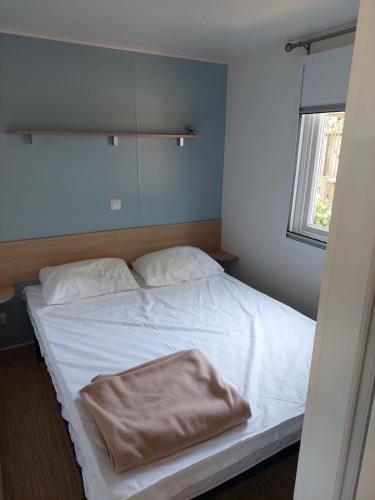 - une chambre avec un lit doté de draps blancs et une fenêtre dans l'établissement Mobil home 6/8 personnes, à Longeville-sur-Mer