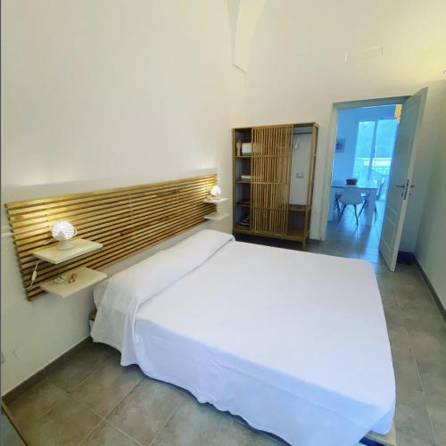 Un dormitorio con una gran cama blanca y una mesa en RESIDENCE IL GIARDINO DI DONNA LEDA, en Castro di Lecce