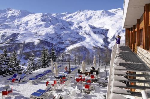 a woman standing on a balcony overlooking a snowy mountain at Belambra Clubs Les Menuires - Neige Et Ciel in Les Menuires