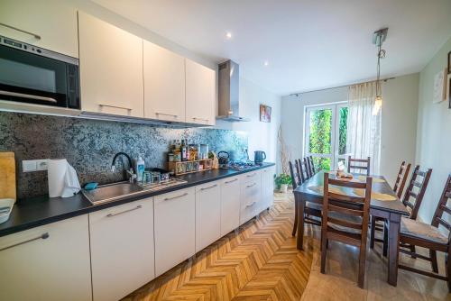 a kitchen with white cabinets and a table and chairs at Willa Michalinka in Jastarnia