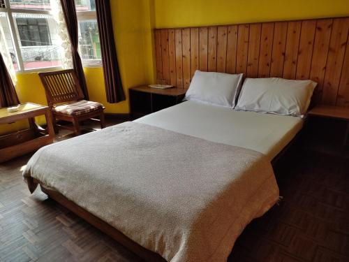 a bedroom with a large bed and a chair at Hotel Mhelung in Darjeeling