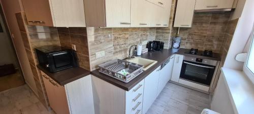 a small kitchen with a sink and a microwave at Platán Apartman in Veszprém