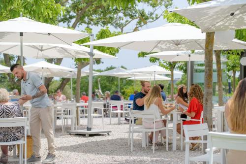 a group of people sitting at tables under umbrellas at Clos des Oliviers Grimaud - Meublé de Tourisme in Grimaud