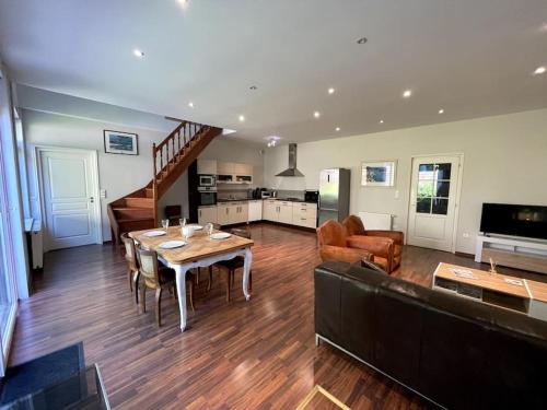 Il comprend un grand salon avec une table et une cuisine. dans l'établissement La Liberté, Loft 90 m2 rénové centre-ville, terrasse amenagee, jeux & parking, à Cambrai