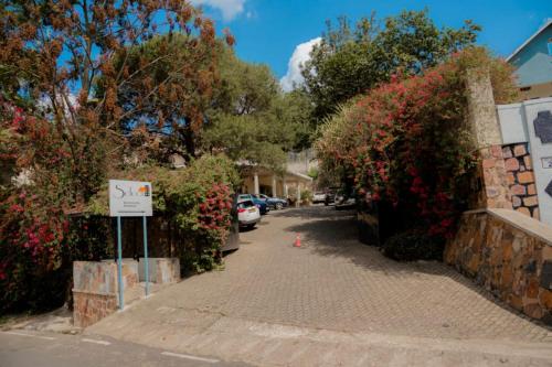 a street with flowering bushes and a sign on the sidewalk at Select Boutique Hotel Kigali in Kigali