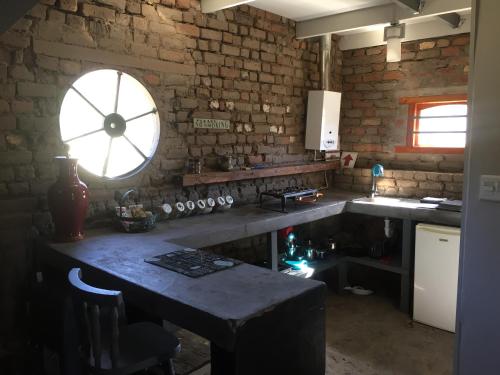 eine Küche mit einem Tisch und einem großen Fenster in der Unterkunft Die Kapokbosskuur in Nieu-Bethesda