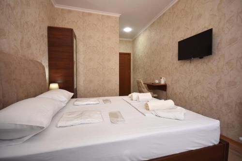 a bedroom with a white bed with a television on the wall at Hotel & Restaurant Sokhumi in Zugdidi