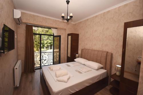 una camera da letto con un letto con lenzuola bianche e una finestra di Hotel & Restaurant Sokhumi a Zugdidi
