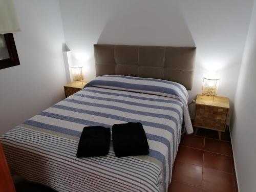 una camera da letto con un letto con due cuscini neri sopra di Apartamentos Risco Verde a Arinaga