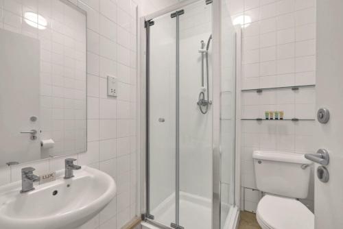 a bathroom with a shower and a toilet and a sink at Bedford Place Hostels in London