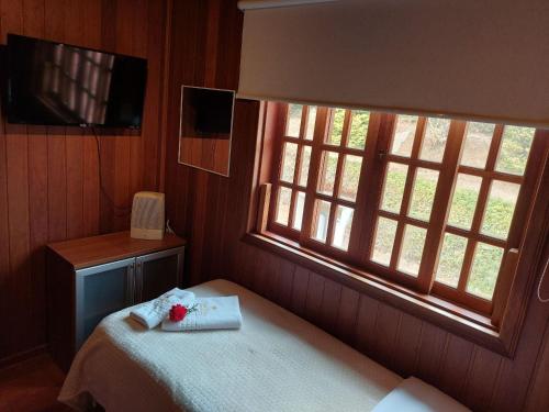 a bedroom with a bed and a window at Mansão Austríaca Guesthouse in Campos do Jordão