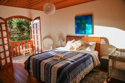 a bedroom with a bed with a blue and white blanket at Mansão Austríaca Guesthouse in Campos do Jordão