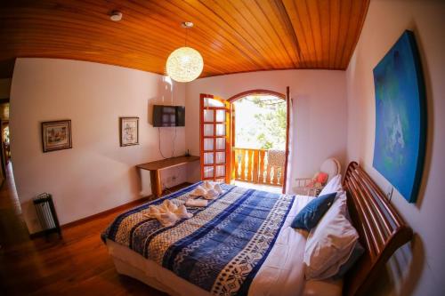 a bedroom with a bed in a room with a window at Mansão Austríaca Guesthouse in Campos do Jordão