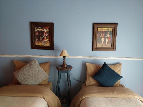 a bedroom with two beds and two pictures on the wall at Mansão Austríaca Guesthouse in Campos do Jordão