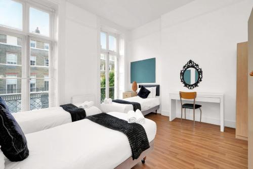a white room with two beds and a mirror at Bedford Place Hostels in London