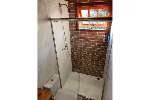 a bathroom with a toilet and a glass shower at Mansão Austríaca Guesthouse in Campos do Jordão
