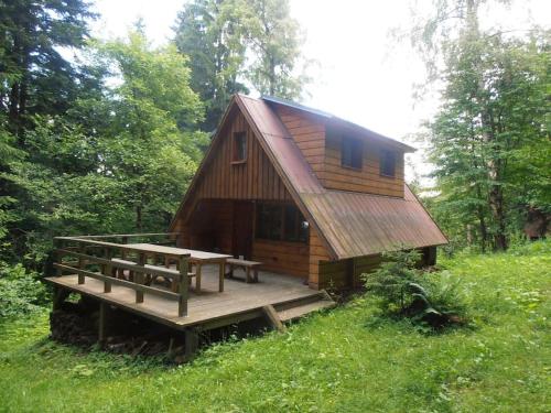 una cabina con terrazza in legno e tavolo di Roztomilá a utulná chata Azzy na samotě v lese. a Valašské Klobouky
