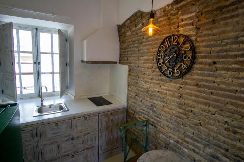 a kitchen with a brick wall and a clock on the wall at Apartamentos Sharis in Jerez de la Frontera