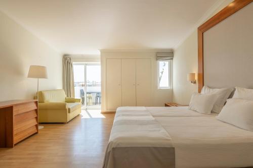 Lagoa Hotel في لاغوا: غرفة فندقية بسرير كبير وكرسي