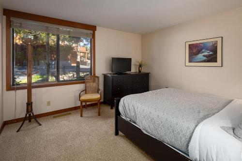 a bedroom with a bed and a chair and a window at Granite River Retreat at Alpine Meadows in Alpine Meadows