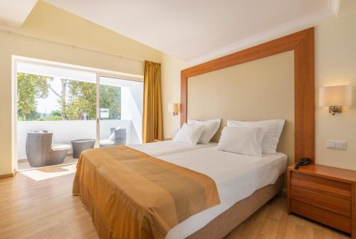 a bedroom with a large bed and a large window at Lagoa Hotel in Lagoa