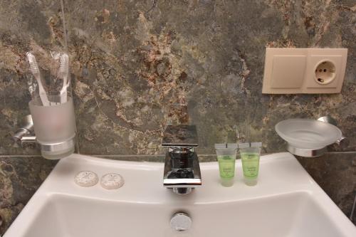 a bathroom sink with two glasses and a faucet at Hotel & Restaurant Sokhumi in Zugdidi