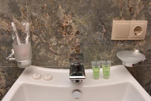 Hotel & Restaurant Sokhumi في زوغديدي: مغسلة الحمام فيها كأسين وصنبور
