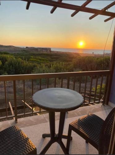 una mesa y sillas en un balcón con vistas a la puesta de sol en Sunset Views Paphos en Pafos