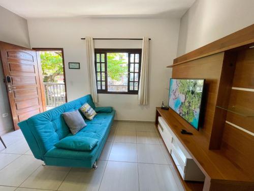 uma sala de estar com um sofá azul e uma televisão em Apto Funcional próximo a Orla do Centro HS4 em Ubatuba