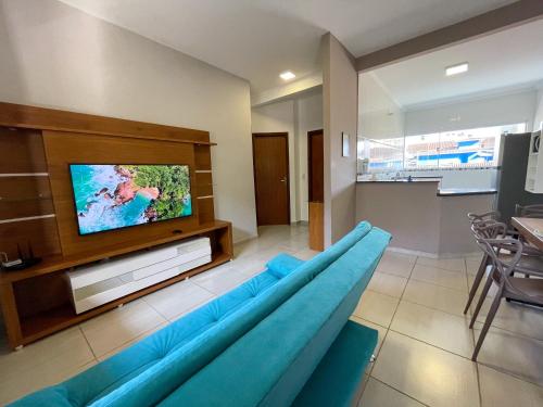 a living room with a blue couch and a flat screen tv at Apto Funcional próximo a Orla do Centro HS4 in Ubatuba