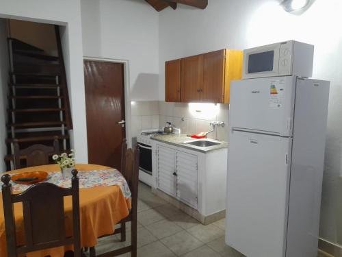 a small kitchen with a white refrigerator and a table at LAS MARIAS - CHAJARI in Chajarí
