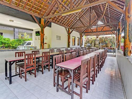 a restaurant with a long table and wooden chairs at Hotel Diana 1 in Denpasar