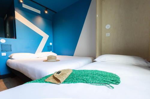Dos camas en una habitación con sombrero en ibis Budget La Rochelle Centre, en La Rochelle