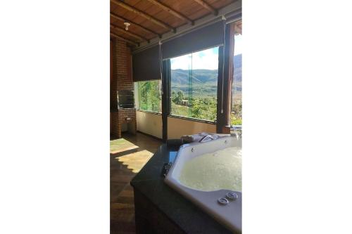 a bathroom with a tub and a large window at Casa do Vaz Lapinha da Serra in Santana do Riacho
