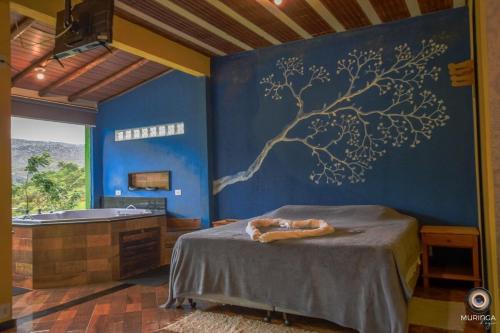 a bedroom with a tree mural on the wall at Casa do Vaz Lapinha da Serra in Santana do Riacho