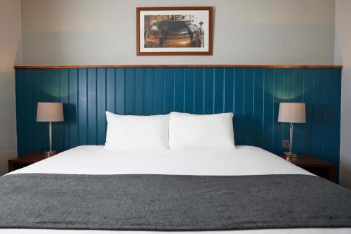 1 dormitorio con 1 cama grande y pared azul en The Longshoot, en Nuneaton