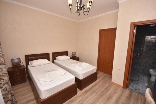 a bedroom with two beds and a chandelier at Hotel & Restaurant Sokhumi in Zugdidi