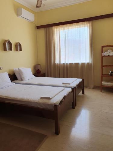 two beds in a room with a window at Sunny House in Vathí