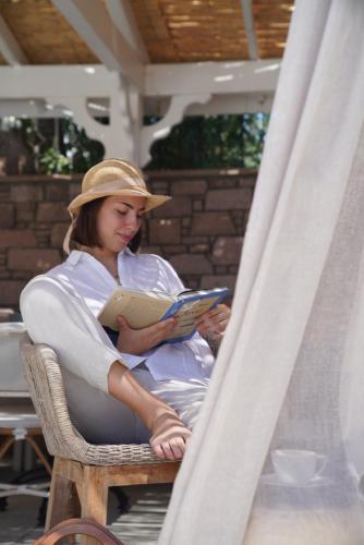 a woman sitting in a chair reading a book at Kapya Cunda in Ayvalık