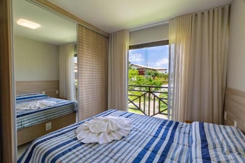 a bedroom with a blue and white bed and a window at Ykutiba Imbassaí - Apartamento Superior - I104 in Imbassai