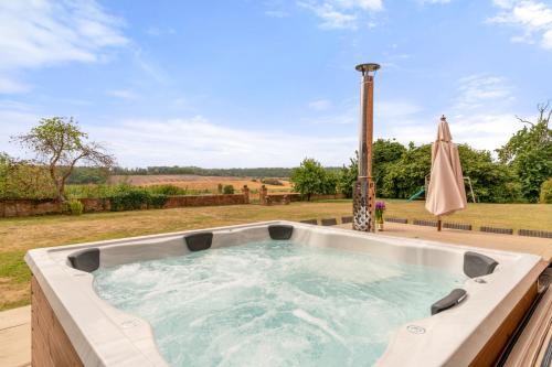 a hot tub on a deck with an umbrella at The Hunting Lodge at Ragley Estate in Alcester