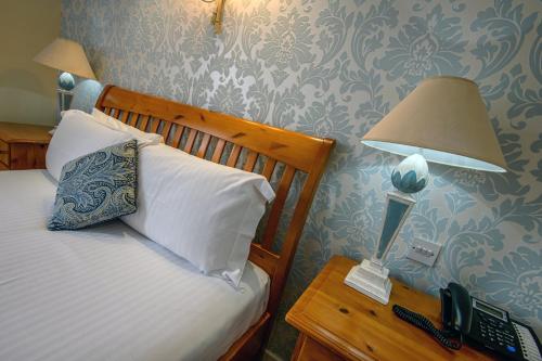 a bedroom with a bed with a lamp and a telephone at The Portland Hotel in Lybster