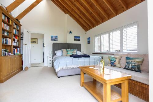 a bedroom with a bed and a couch and a table at Linden House in West Wittering