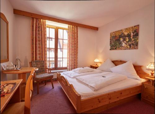 Hotel der Löwen in Staufen في ستوفت ام بريسغو: غرفه فندقيه بسرير ومكتب ونافذه